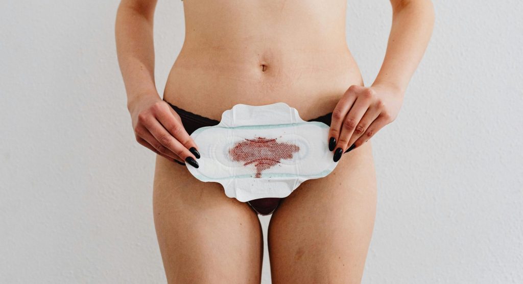 femme qui tient une serviette hygiénique ensanglée