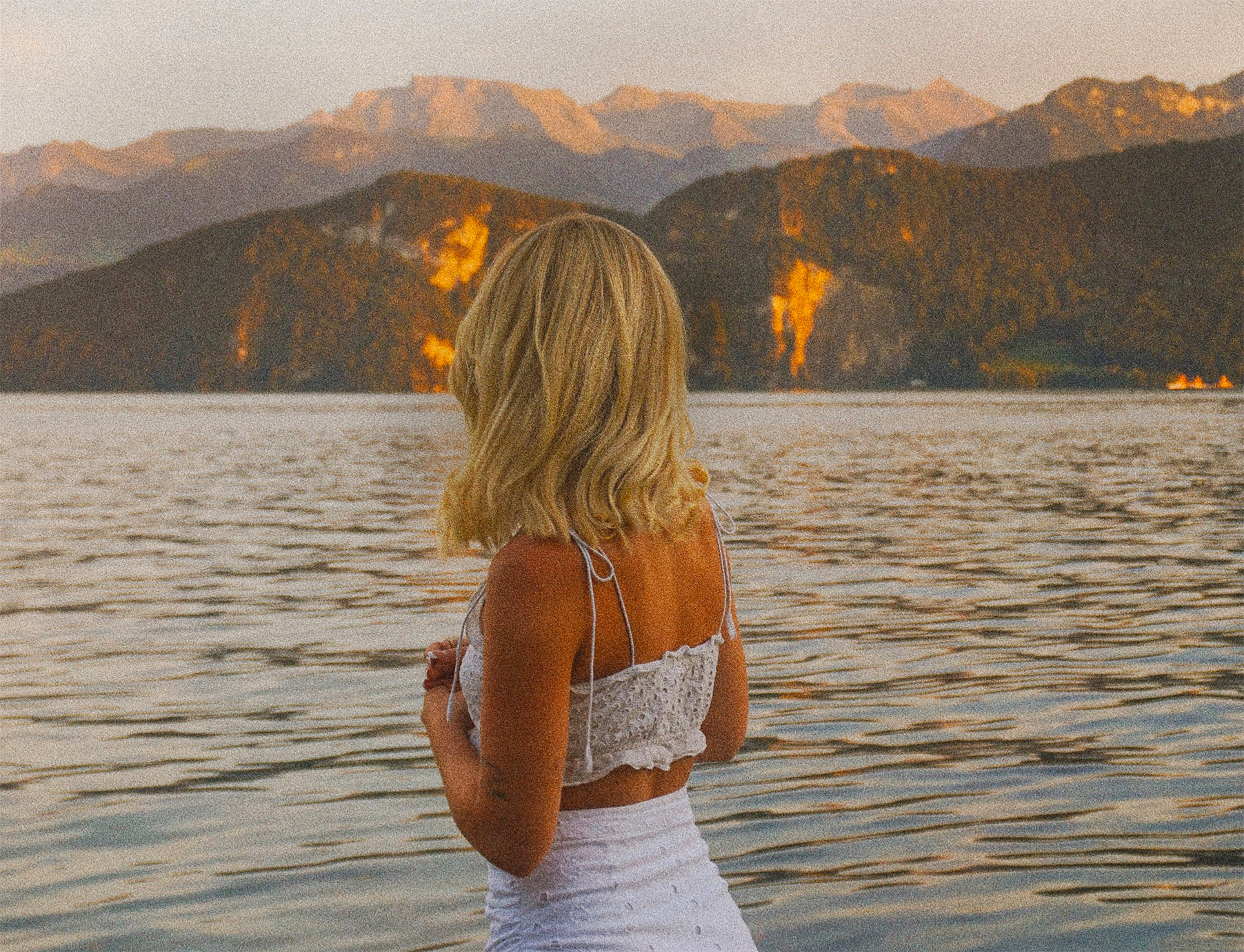 Femme sereine profitant d'un paysage de vacances au coucher du soleil, en illustration du guide pratique What The Flux pour vivre ses règles abondantes en été.